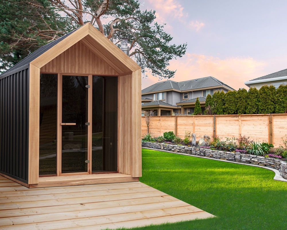 Leisurecraft Hudson sauna on a green lawn surrounded by a wooden fence and residential houses at dusk|||
