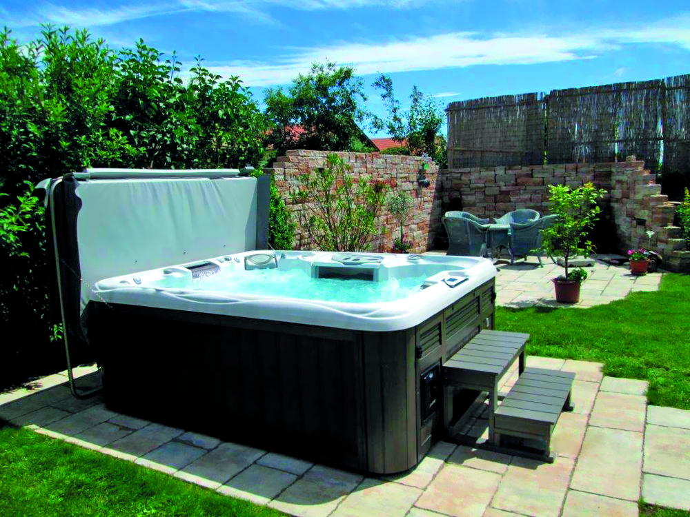 hot tub with opened cover in a backyard|waterfall feature in hot tub|control panel feature of a hot tub|hot tub jets|family is having fun in hot tub|hot tub led lights feature