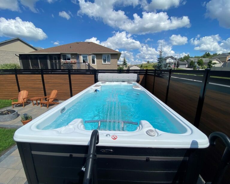 swim spa installed in the backyard surrounded by a wooden fence|grandparents with their grandchildren enjoying their time in a swim spa|Wooden deck with installed swim spa and chairs