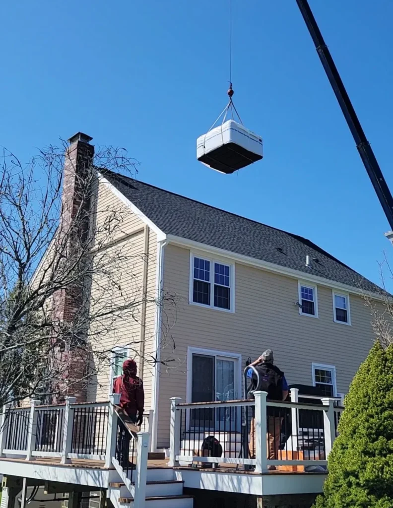 Crane lifting hot tub over house for backyard installation