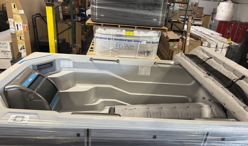 Swim spa in warehouse with plastic wrap around it.